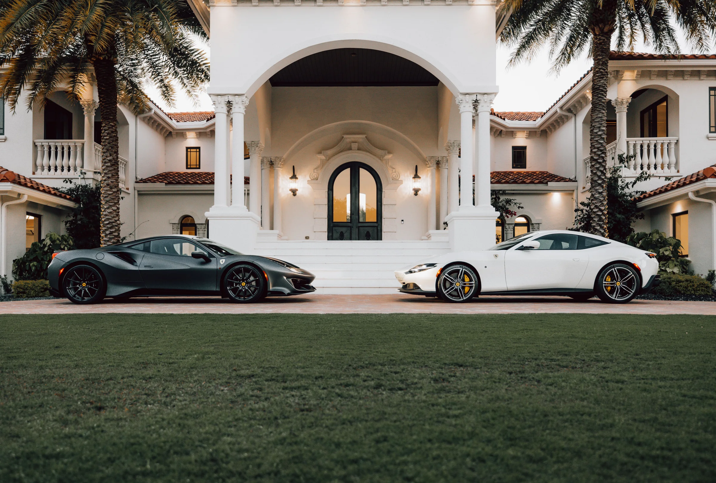 Exotic sports cars positioned in front of a luxury estate
